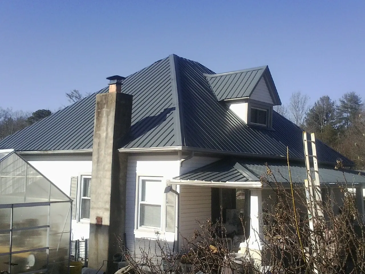 Dark blue standing seam metal roof on a white farmhouse with dormer — Slate & Tile Roof Repair by Roofing Brothers in Loami