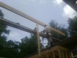 Carpenter setting a ridge beam over a new addition frame — Ice Dam Removal by Roofing Brothers in Loami