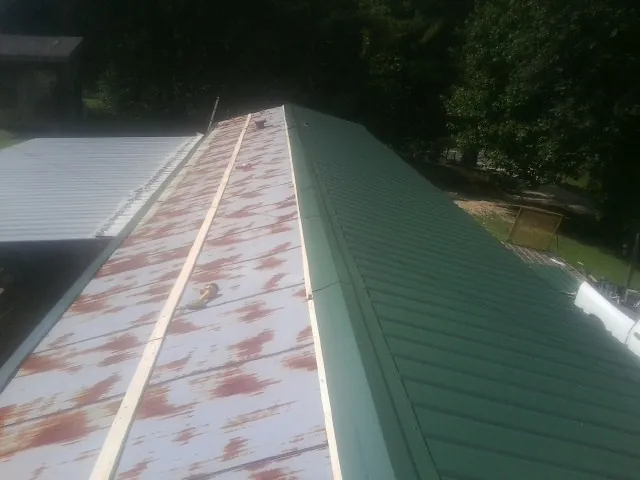 Old rusted panels beside newly installed green metal roofing — Wind Damage Roof Repair by Roofing Brothers in Loami