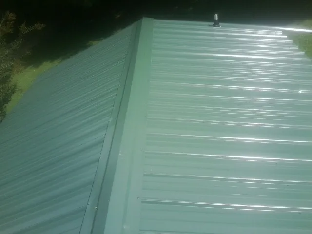 New green metal panels meeting at the ridge of a roof — Flat Roof Repair work by our crew in Loami