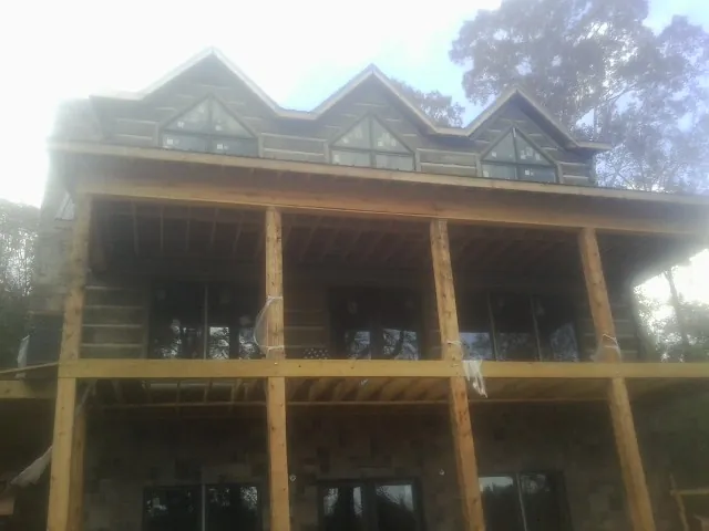 Dormers and porch framing on a large log home under construction — Roof Coating work by our crew in Loami