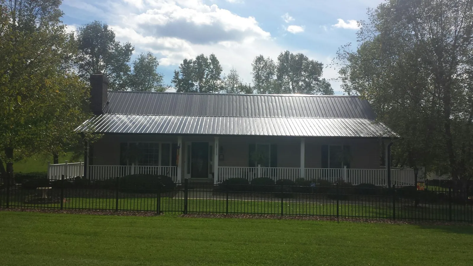 Gray metal roof on a brick ranch with a full width front porch — Gutter Guard Installation work by our crew in Loami
