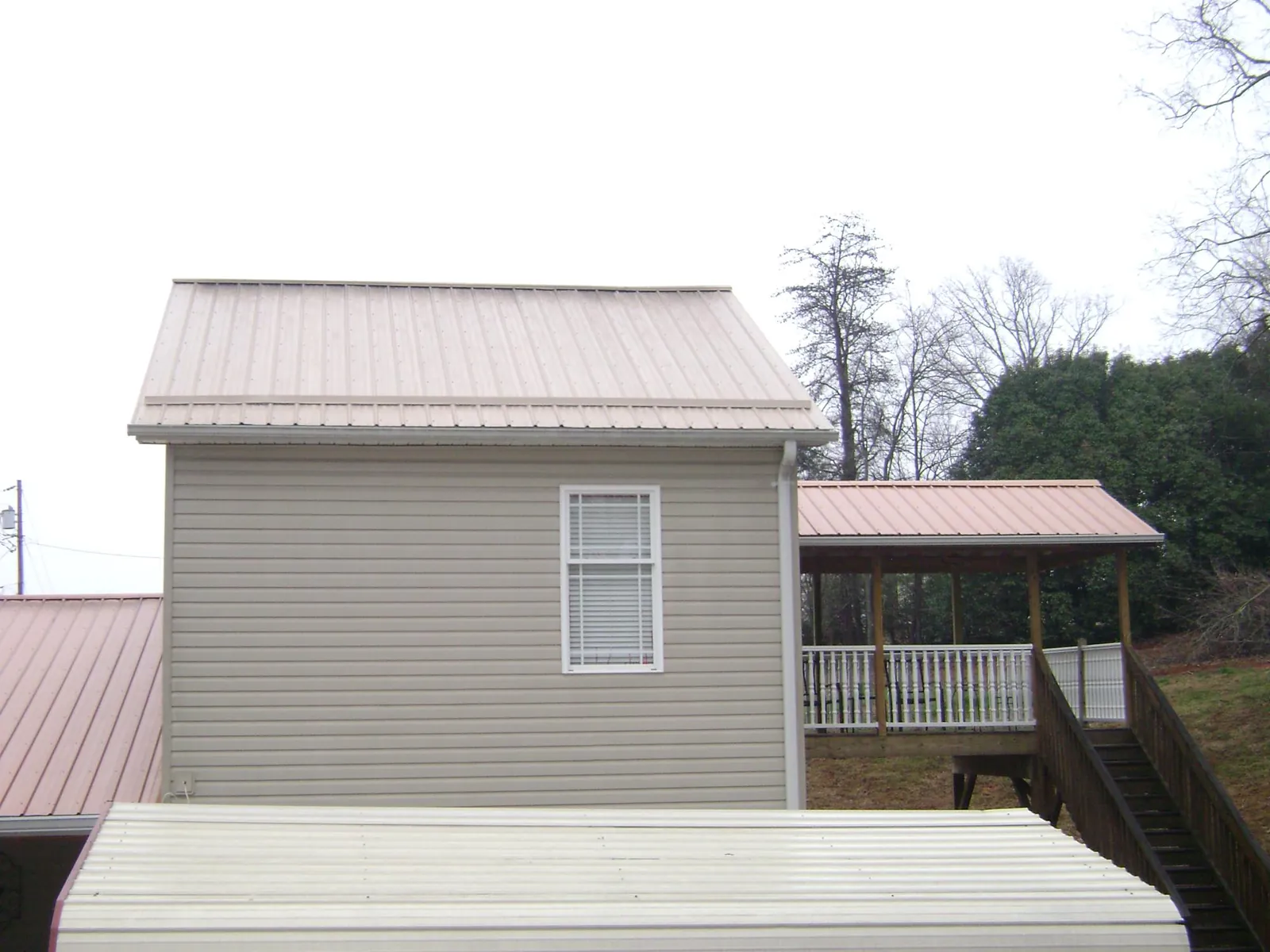 Tan metal roofs on a two story addition and attached porch, from a Roof Replacement job in Loami