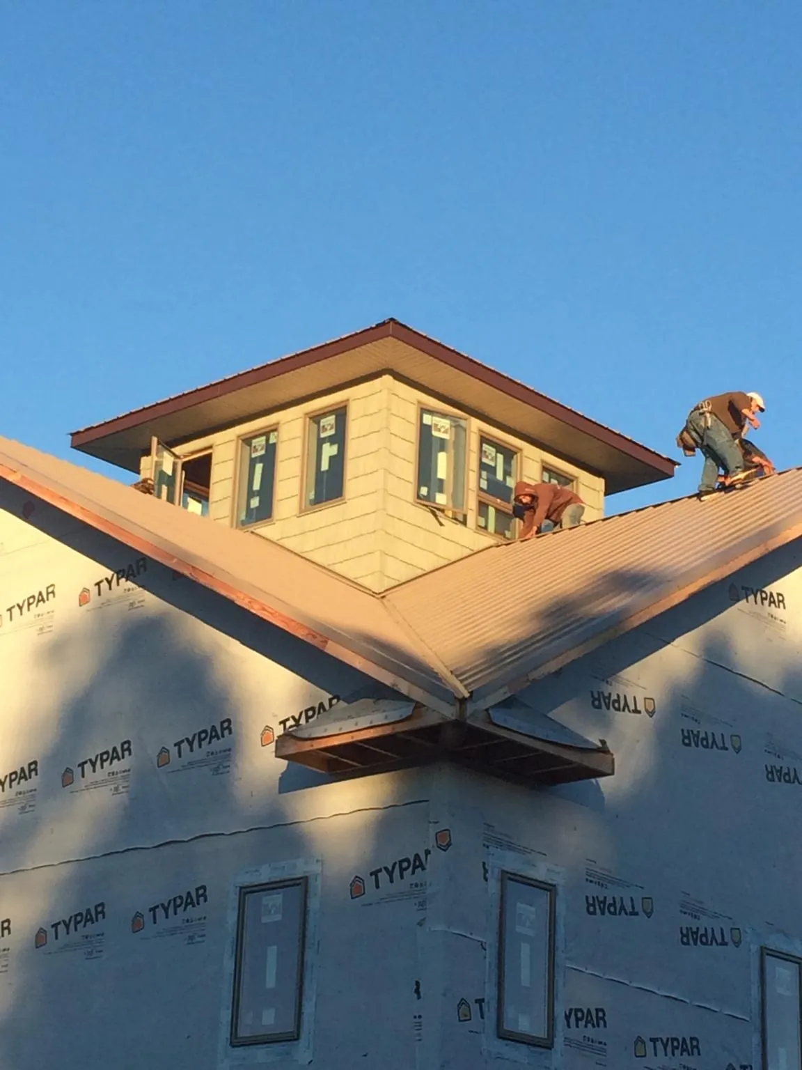Roofers working around a rooftop cupola on a new metal roof at sunset — Roof Waterproofing in Loami by Roofing Brothers